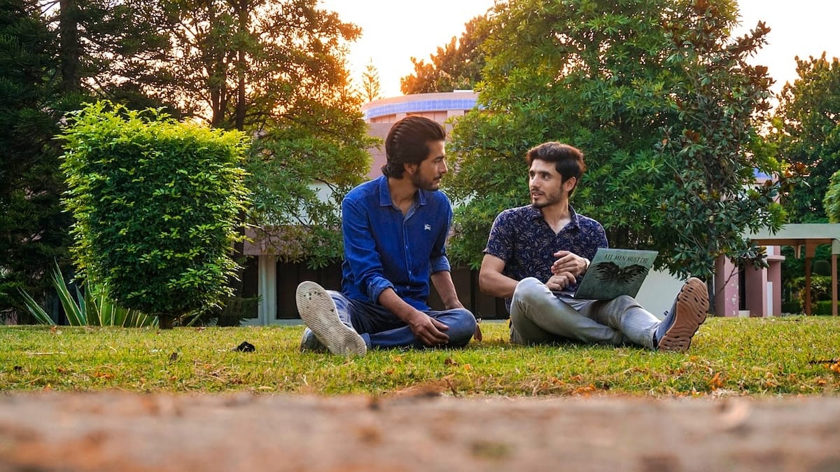 Male students sitting outside on campus