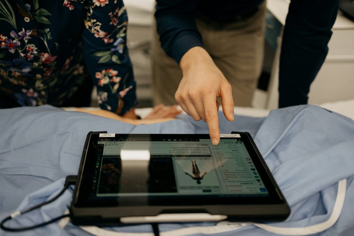 Two people standing with a digital tablet displaying a medical simultation