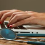 Person typing on a laptop computer with a stethoscope
