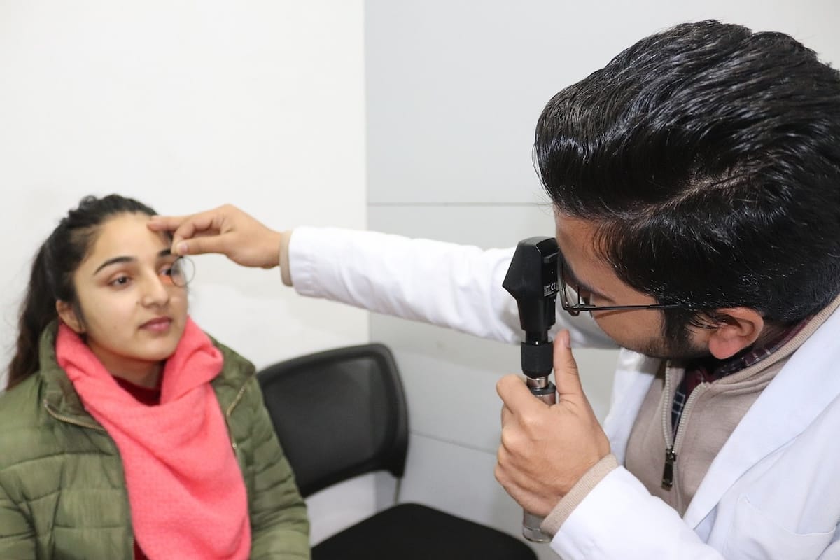 Medical professional in a laboratory coat checking patient's eye