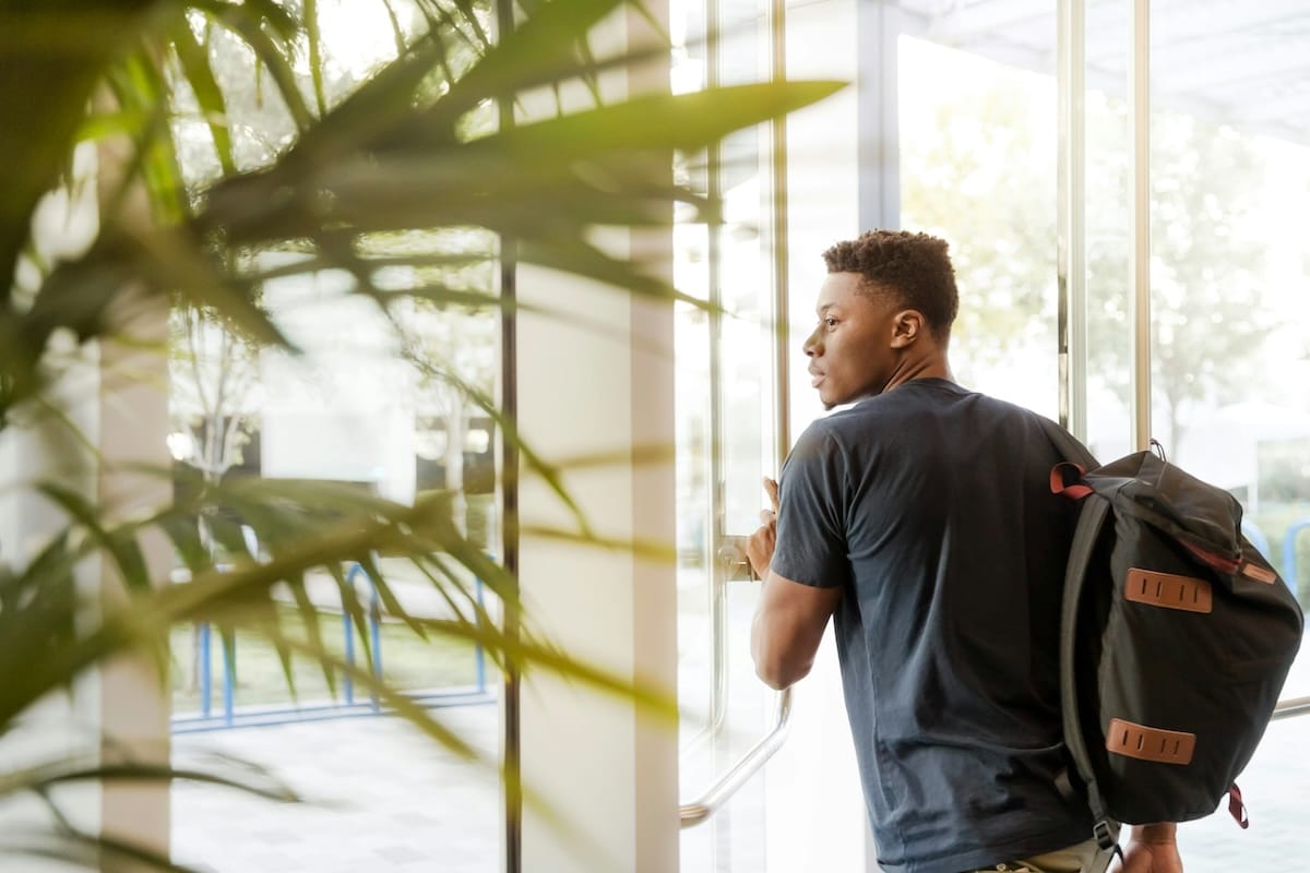 Individual student walking through a door with a backpack