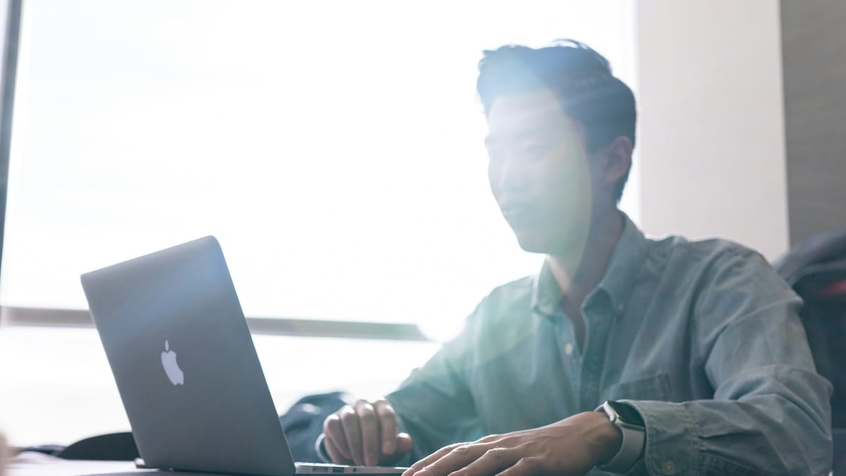 Student studying with laptop computer beside a window