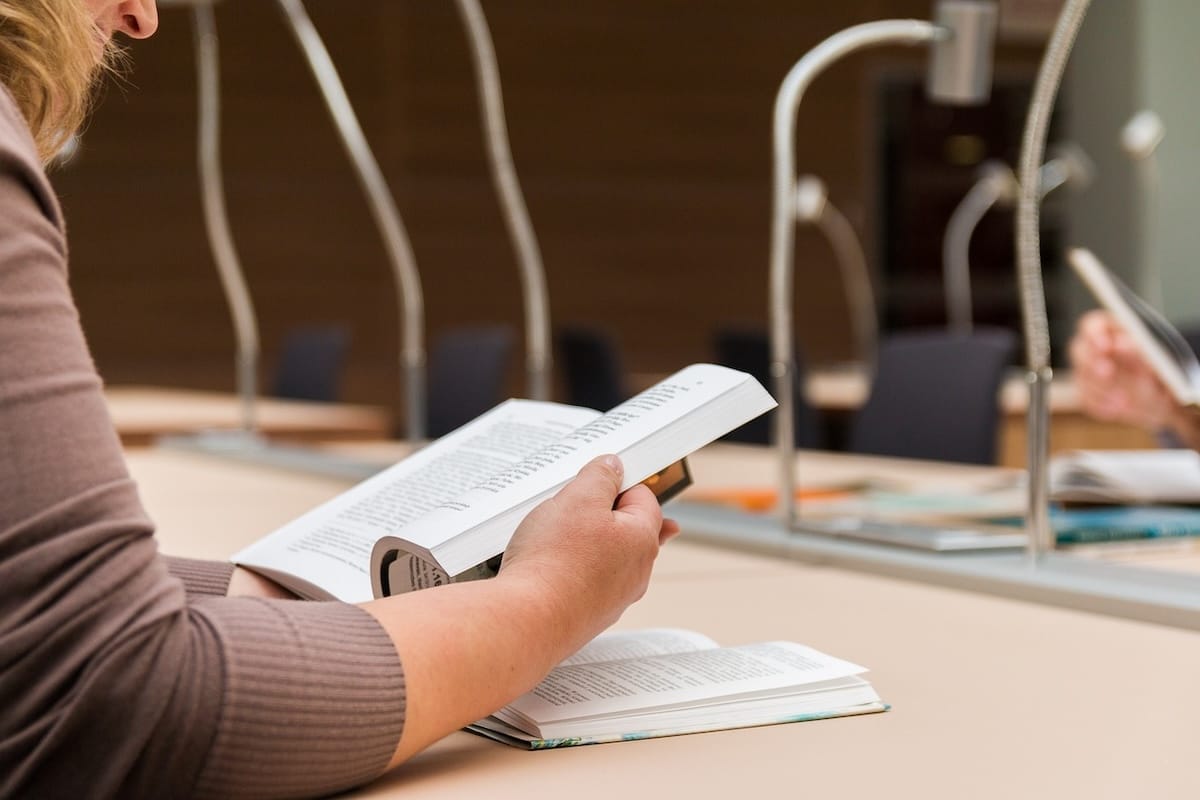 Individual sitting at a table indoors with two books